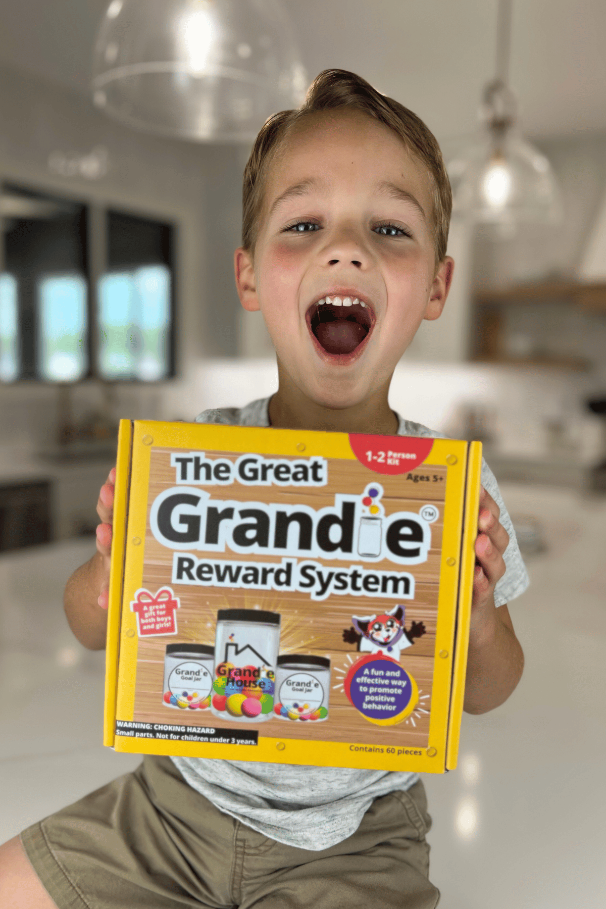 Young child holding The Great Grandie Reward System box with a huge joyful expression on his face.